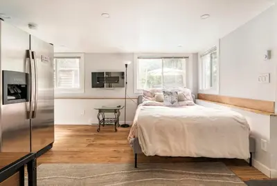 a white bedroom with a bed and a refrigerator at Resort style home living in Delta
