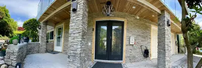 a stone house with a black door with a wooden ceiling at Resort style home living in Delta