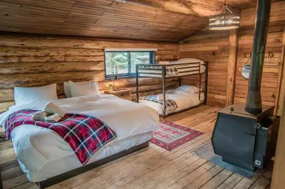 a bedroom with two beds in a log cabin at Chute Lake Lodge in Naramata