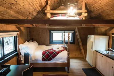 a bedroom in a log cabin with a bed in it at Chute Lake Lodge in Naramata