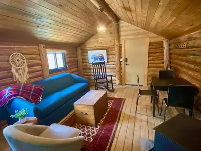 a living room with a blue couch in a log cabin at Chute Lake Lodge in Naramata