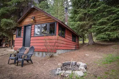 a small cabin with two chairs in front of it at Chute Lake Lodge in Naramata