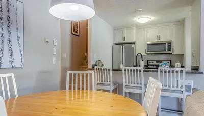 a kitchen and dining room with a wooden table and chairs at Crystal Forest #29 by Bear Country in Sun Peaks
