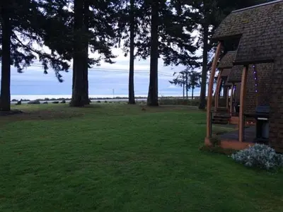 a house in a field with trees and green grass at Oyster Bay Resort in Oyster Bay