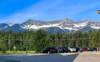 a parking lot with cars parked in front of mountains at Riverside Condos by Fernie Central Reservations in Fernie