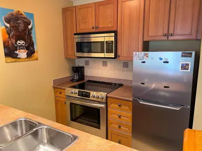 a kitchen with a stainless steel refrigerator and a sink at Snow Creek Lodge by Fernie Central Reservations in Fernie