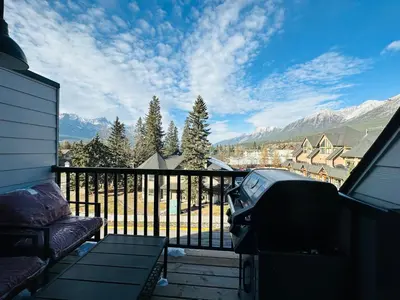 a balcony with a couch and a view of the mountains at 2-in-1 Skyline MTN Retreat - Hot Tub - Pool - AC in Canmore