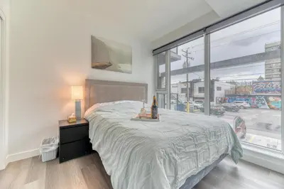 a bedroom with a bed and a large window at Kensington Suite 2bed & 1bath in Calgary