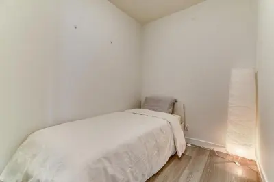 a white bedroom with a bed and a lamp at Kensington Suite 2bed & 1bath in Calgary
