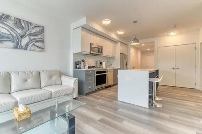 a living room with a white couch and a kitchen at Kensington Suite 2bed & 1bath in Calgary