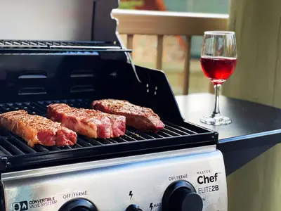 a grill with meat and a glass of red wine at Windtower Lodge FullKitchen-Kingbed Suite-MntView-UGParking-Walk2DT in Canmore