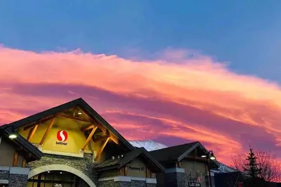 a building with a cloudy sky in the background at Windtower Lodge FullKitchen-Kingbed Suite-MntView-UGParking-Walk2DT in Canmore