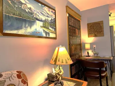 a living room with a desk and a lamp on a table at Windtower Lodge FullKitchen-Kingbed Suite-MntView-UGParking-Walk2DT in Canmore