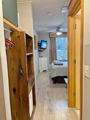 a room with a bedroom with a bed and a television at Windtower Lodge Queen Bed Suite-UGParking&Walking2DT in Canmore