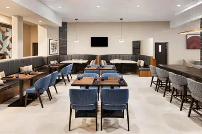a restaurant with tables and chairs and a flat screen tv at Delta Hotels by Marriott Grande Prairie Airport in Grande Prairie