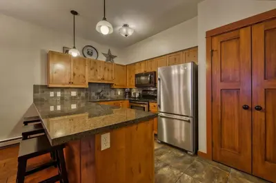 a kitchen with wooden cabinets and a stainless steel refrigerator at Settlers Crossing #08 by Bear Country in Sun Peaks
