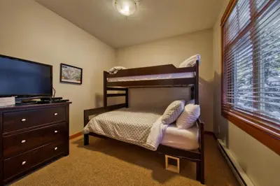 a bedroom with a bunk bed and a television at Settlers Crossing #08 by Bear Country in Sun Peaks