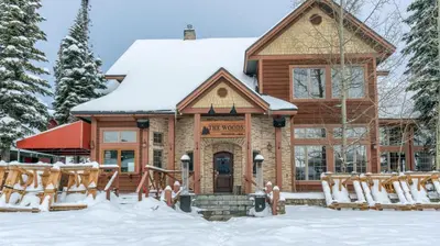 a log cabin in the snow with snow covered chairs at Forest Lane Hideaway - Luxurious Family Friendly Home w Private Hot Tub in Big White