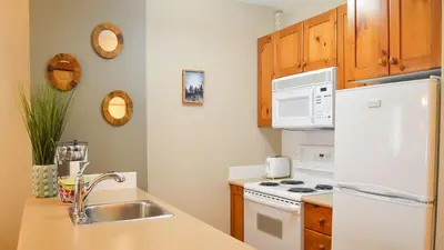 a kitchen with a white refrigerator and a sink at Fireside Lodge #215 by Bear Country in Sun Peaks
