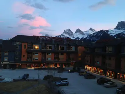 a hotel with snow capped mountains in the background at Apartment 407, Contemporary Decor in Canmore