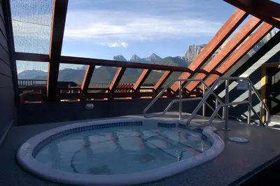 a hot tub on a balcony with a view of the mountains at Apartment 407, Contemporary Decor in Canmore
