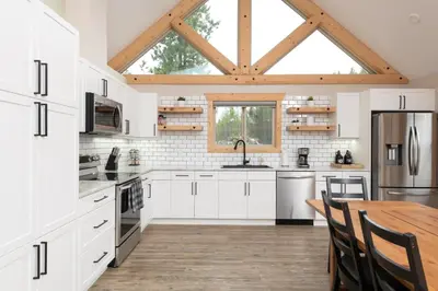 a kitchen with white cabinets and a wooden table at Lazy Moose in Valemount