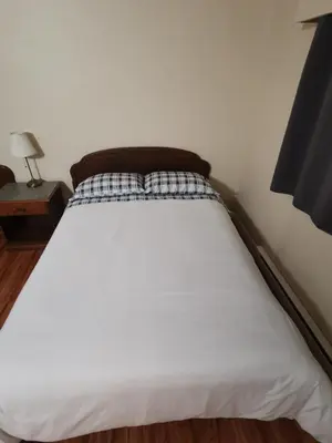 a white bed in a bedroom with a night stand at Coquihalla Motel in Hope