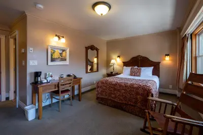 a hotel room with a bed and a desk and a mirror at Kaslo Hotel in Kaslo