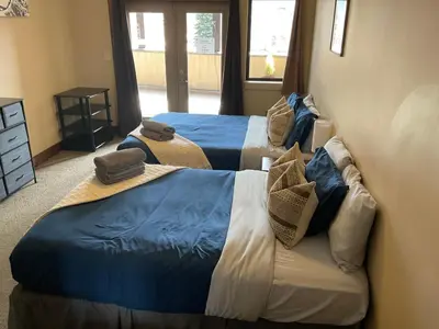 two beds in a room with blue and white at Lily glacier suite at silver bear condos in Revelstoke