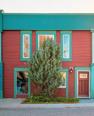 a red building with a tree in front of it at The Hidden Hollow Suite - Downtown in Drumheller