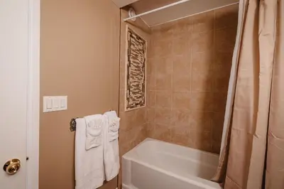 a bathroom with a tub and a toilet and a shower at The Hidden Hollow Suite - Downtown in Drumheller