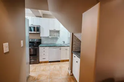a kitchen with white cabinets and a tile floor at The Hidden Hollow Suite - Downtown in Drumheller