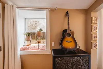 a guitar hanging on a wall next to a window at The Hidden Hollow Suite - Downtown in Drumheller