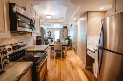 a kitchen with stainless steel appliances and wooden floors at The Watermark Suite - Downtown in Drumheller