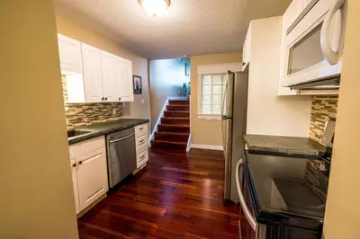 a kitchen with white cabinets and wood floors and a kitchen with a stove at The River Blossom Suite - Downtown in Drumheller