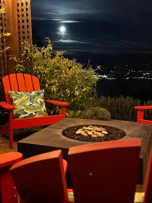 a fire pit on a patio with a view of the city at Les Chambres Roses in West Kelowna