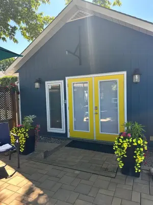 a blue house with yellow doors and flowers at K STREET CARRIAGE HOUSE Studio in Penticton