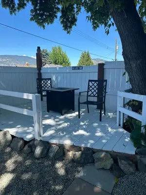 a patio with two chairs and a table and a white fence at K STREET CARRIAGE HOUSE Studio in Penticton