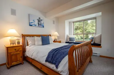 a bedroom with a wooden bed and a window at 2BR in Symphony, Dog Friendly, Hot Tub, Private Balconies, Village Location, Parking in Whistler