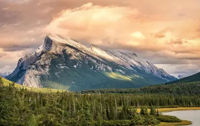 a snow covered mountain with a river and trees at Cozy 2 BR - King and Queen Condo Sleep up to 6 for WFH & Vacation in Canmore