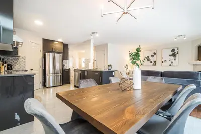 a kitchen and dining room with a wooden table and chairs at Spa Oasis Home - Hot Tub - King Bed - BBQ - Garage - Pets! in Edmonton