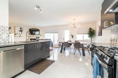 a kitchen with a stove and a dining room at Spa Oasis Home - Hot Tub - King Bed - BBQ - Garage - Pets! in Edmonton