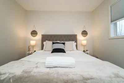 a bedroom with a large white bed with two lamps at Spa Oasis Home - Hot Tub - King Bed - BBQ - Garage - Pets! in Edmonton
