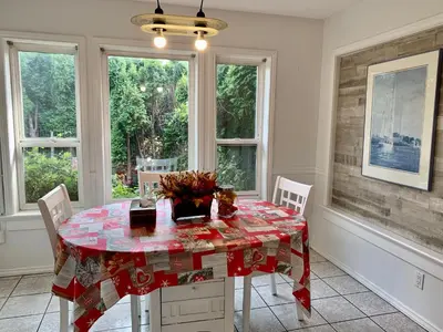 a dining room with a table and chairs and windows at One Bedroom queen bed Sharing Washroom in Tiger Sweet House License## in Richmond