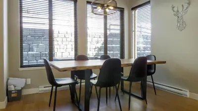 a dining room table and chairs in a room with windows at Echo Landing #22 by Bear Country in Sun Peaks