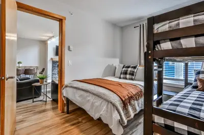 a bedroom with a bunk bed and a living room at CHARMING 1 Bdrm plus loft with VIEWS managed by Little Sister Getaways in Canmore