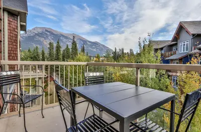 a table and chairs on a balcony with a mountain at CHARMING 1 Bdrm plus loft with VIEWS managed by Little Sister Getaways in Canmore