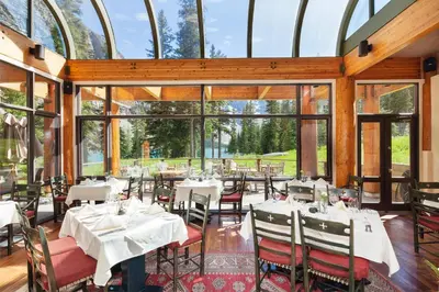 a restaurant with tables and chairs and windows at Moraine Lake Lodge in Lake Louise