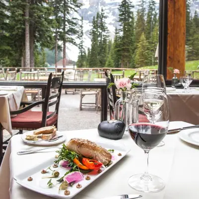 a table with a plate of food and a glass of wine at Moraine Lake Lodge in Lake Louise