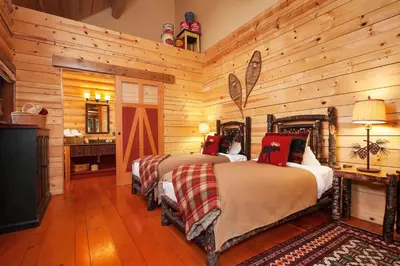 two beds in a room with wooden walls at Cathedral Mountain Lodge in Field